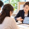 相談ブースでタブレットの積み立てグラフを夫婦に見せて説明する女性アドバイザー