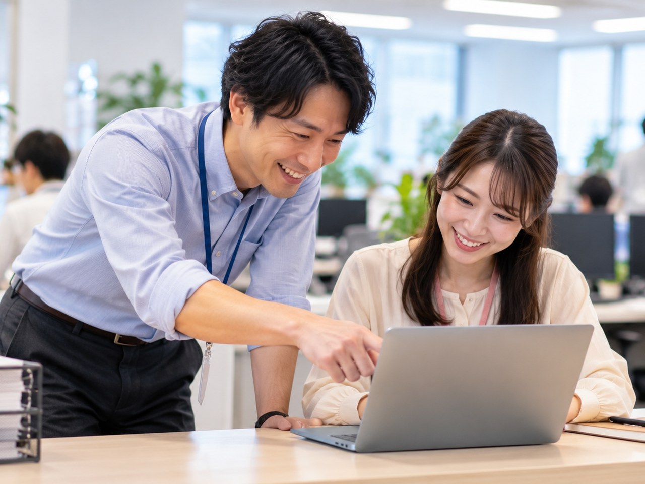社内のIT窓口で同僚のノートパソコンの設定を手伝う男性社員