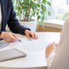 オフィスの面談スペースで書類を前に話す二人の手元